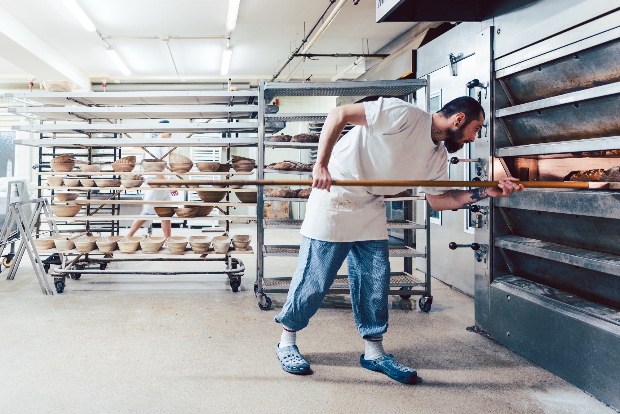 Bäcker schiebt Brot mit dem Schieber in den Etagenofen