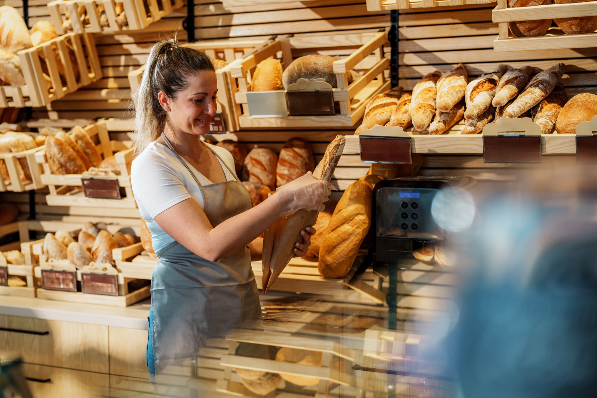 Verkäuferin räumt Brot ins Regal einer Bäckerei